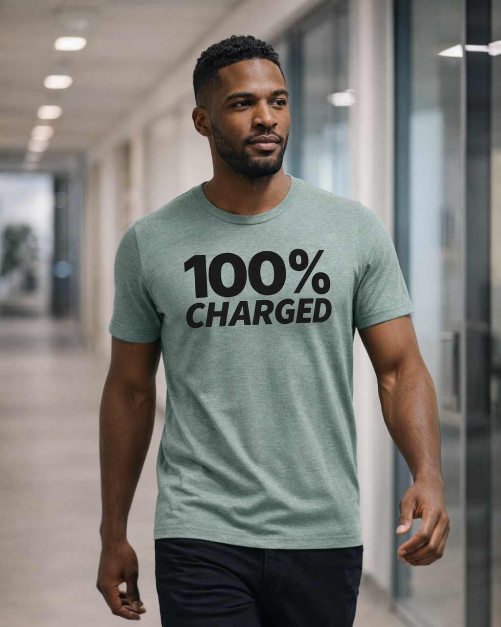 Man wearing a light green t-shirt with '100% Charged' text in a modern indoor setting