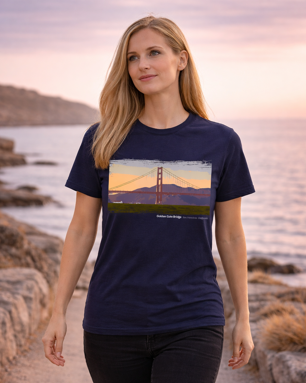 Woman wearing a navy blue t-shirt with a Golden Gate Bridge graphic, standing on a beach.