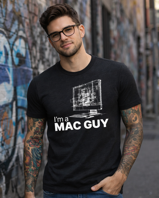 Man wearing a black t-shirt with 'I'm a MAC GUY' text and graphic, standing in front of a graffiti wall.