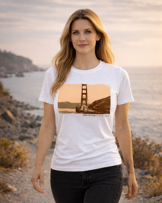 Woman wearing a white t-shirt with a Golden Gate Bridge graphic, standing on a beach.