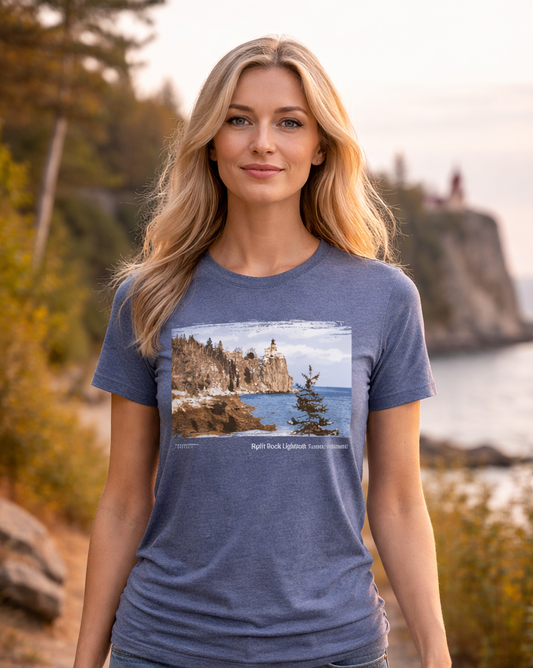 Woman wearing a blue t-shirt with a scenic print, standing outdoors near a body of water.