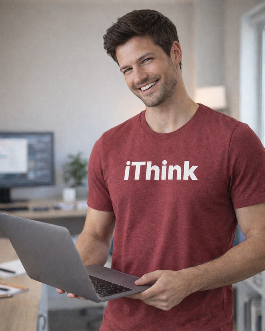 Man wearing a red 'iThink' t-shirt holding a laptop in an office setting